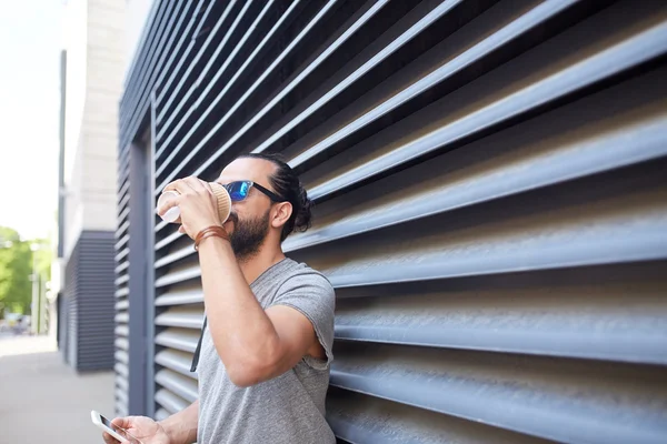 Человек со смартфоном пьет кофе на городской улице — стоковое фото