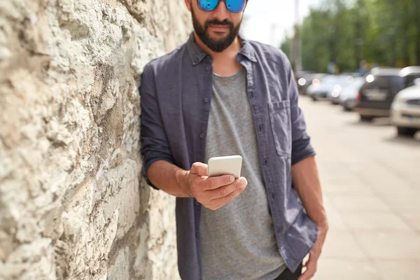 Close up of man with smartphone at stone wall — Stock Photo, Image