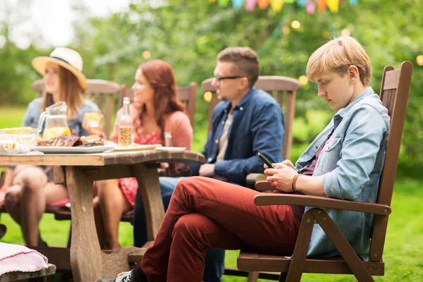 Man met smartphone en vrienden op zomer feest — Stockfoto