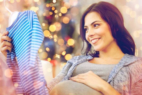 Happy woman holding baby boys bodysuit at home — Stock Photo, Image