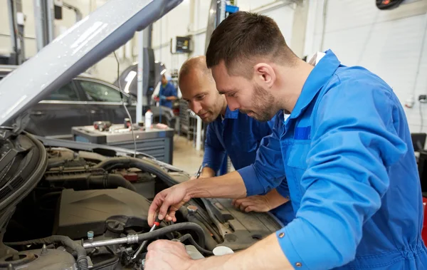 Hombres mecánicos con llave inglesa reparación de coches en el taller — Foto de Stock