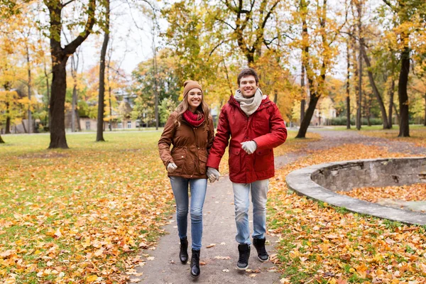 Счастливая молодая пара бежит в осеннем парке — стоковое фото