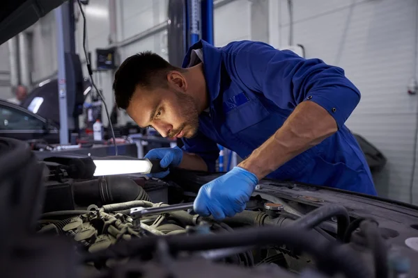 Mecánico hombre con lámpara de reparación de coches en el taller Imagen de stock