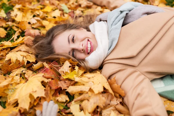 Hermosa mujer feliz acostada en hojas de otoño —  Fotos de Stock