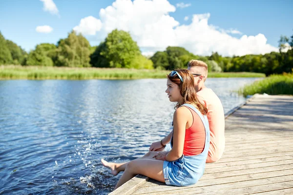 Щаслива підліткова пара сидить на річковому причалі — стокове фото