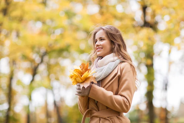 Belle femme avec des feuilles d'érable dans le parc d'automne — Photo