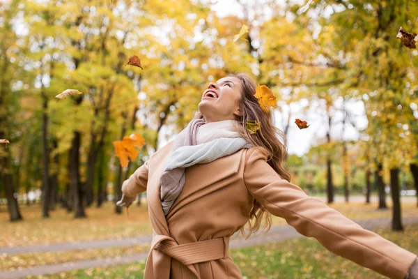 Šťastná žena baví s listy v podzimním parku — Stock fotografie