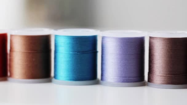 Row of colorful thread spools on table — Stock Video