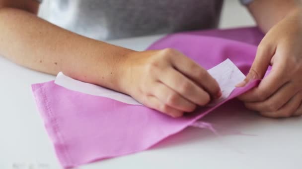 Женщина с булавками сшивает бумажный узор к ткани — стоковое видео