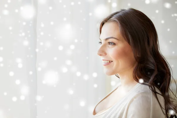 Felice giovane donna guardando attraverso la finestra a casa — Foto Stock