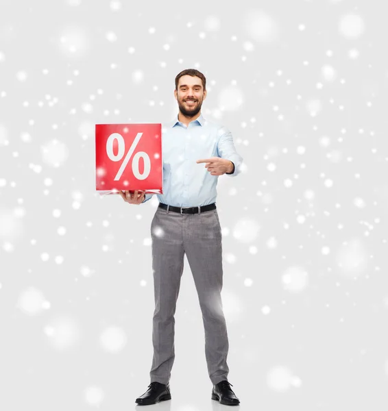 Hombre sonriente con signo de porcentaje rojo sobre la nieve — Foto de Stock