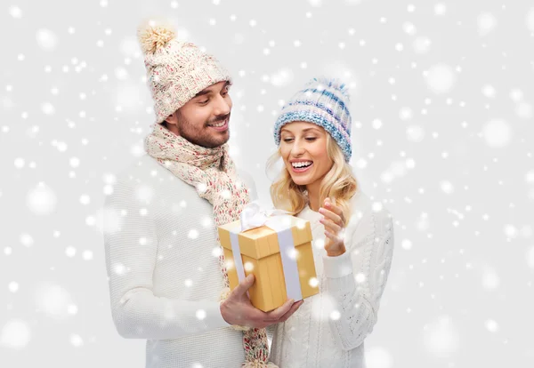 Улыбающаяся пара в зимней одежде с подарочной коробкой — стоковое фото