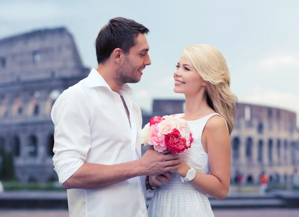 Happy couple with bunch of flowers over coliseum — Stock Photo, Image