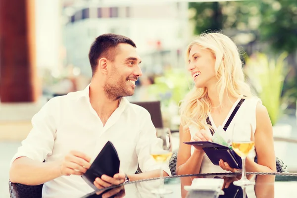 Happy couple with wallet paying bill at restaurant — Stock Photo, Image