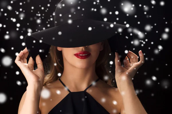 Bella donna in cappello nero sopra la neve — Foto Stock