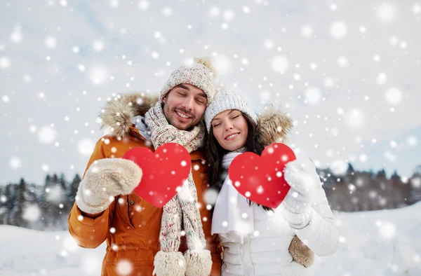 Feliz pareja con corazones rojos sobre el paisaje de invierno — Foto de Stock