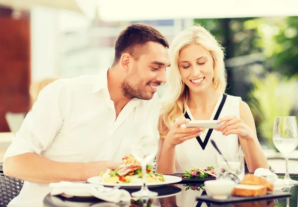 Feliz pareja con smatphone fotografiando comida — Foto de Stock