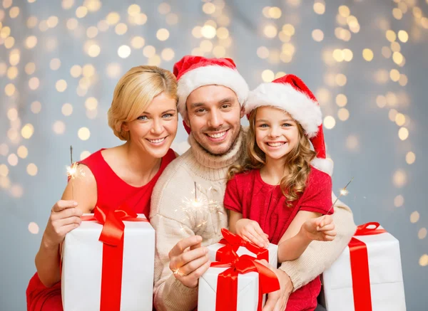Gelukkige familie holding geschenkdozen en sparkles — Stockfoto