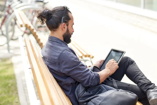 Homem com tablet pc sentado no banco de rua da cidade — Fotografia de Stock