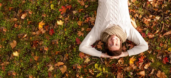 Sonriente joven acostado en el suelo en el parque de otoño —  Fotos de Stock