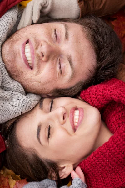 Close up de casal feliz deitado em folhas de outono — Fotografia de Stock