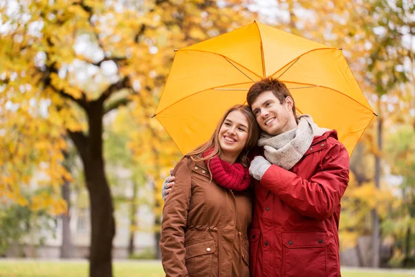 Pareja sonriente con paraguas en el parque de otoño — Foto de Stock