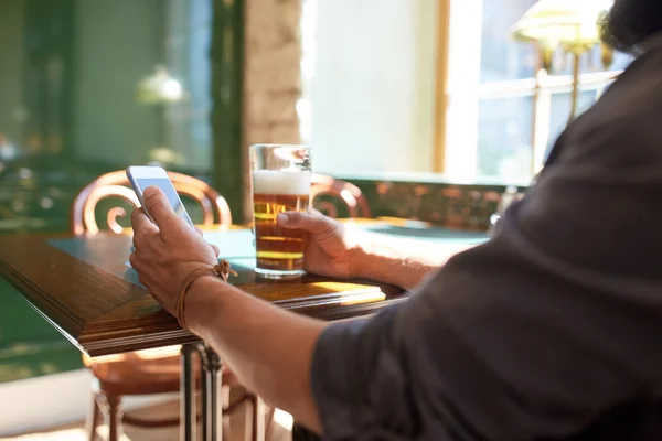 Κοντινό πλάνο του ανθρώπου με το smartphone και μπύρα σε παμπ — Φωτογραφία Αρχείου