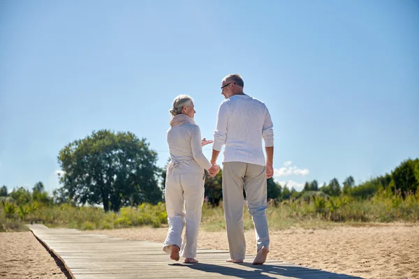 Šťastný pár vysokých hospodářství ruce na letní beach — Stock fotografie