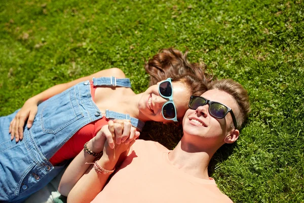 Feliz casal adolescente deitado na grama no verão — Fotografia de Stock