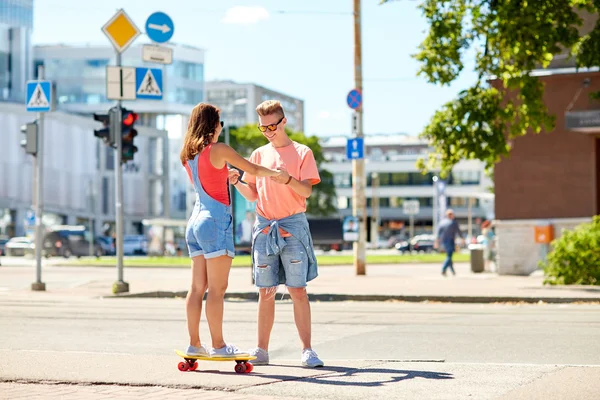 10代のカップルがスケートボードに乗って街を — ストック写真