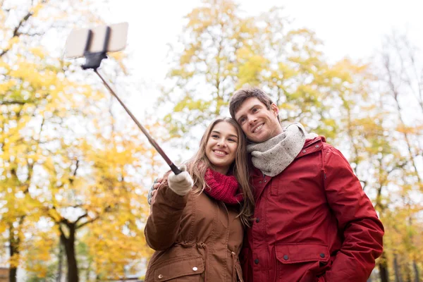 Пара делает селфи на смартфоне в осеннем парке — стоковое фото