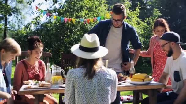 Друзья собираются на ужин в летнем саду — стоковое видео