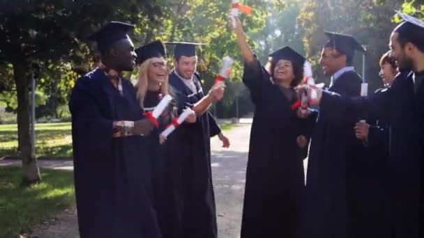 Счастливые студенты в миномётных досках с дипломами — стоковое видео