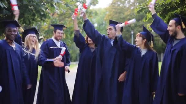 Щасливі студенти в мінометних дошках з дипломами — стокове відео