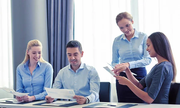 Lächelnde Geschäftsleute mit Papieren im Büro — Stockfoto