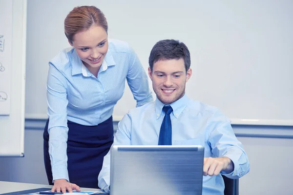 Χαμογελώντας επιχειρηματίες με φορητό υπολογιστή στο γραφείο — Φωτογραφία Αρχείου