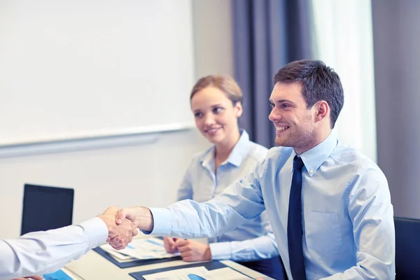 Smiling business team shaking hands in office — Stock Photo, Image