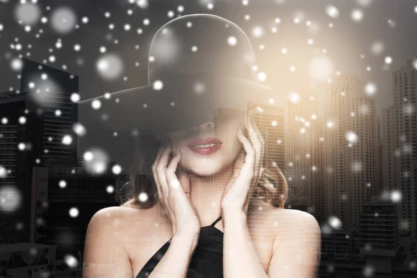 Şehir ve kar üzerinde siyah şapkalı güzel kadın — Stok fotoğraf