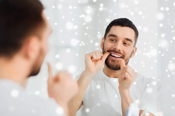 Man med tandtråd rengöring tänder på badrum — Stockfoto