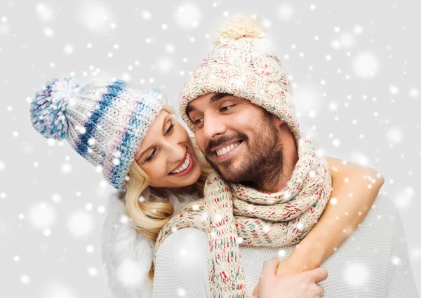 Smiling couple in winter clothes hugging over snow — Stock Photo, Image