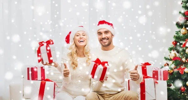 Счастливая пара с рождественскими подарками и большими пальцами вверх — стоковое фото
