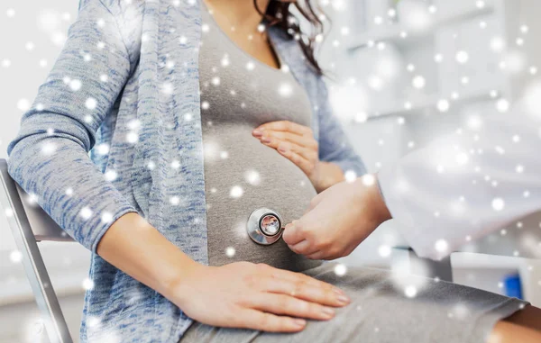 Médico con estetoscopio y vientre de mujer embarazada — Foto de Stock