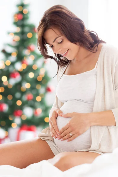 Mulher grávida feliz fazendo coração no Natal — Fotografia de Stock