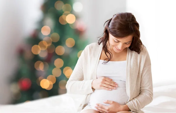 Glada gravida kvinnan sitter på sängen vid jul — Stockfoto