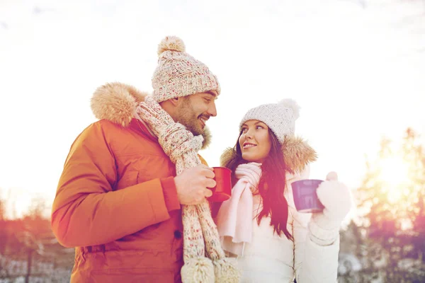 Feliz pareja con tazas de té sobre el paisaje de invierno — Foto de Stock