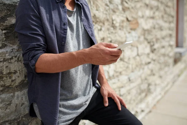 Primer plano del hombre con teléfono inteligente en la pared de piedra —  Fotos de Stock