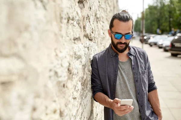 Hombre mensaje de texto en el teléfono inteligente en la pared de piedra — Foto de Stock