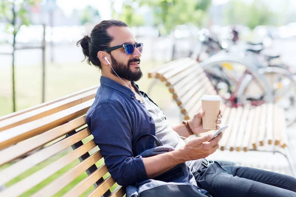 Hombre con auriculares y teléfono inteligente beber café — Foto de Stock