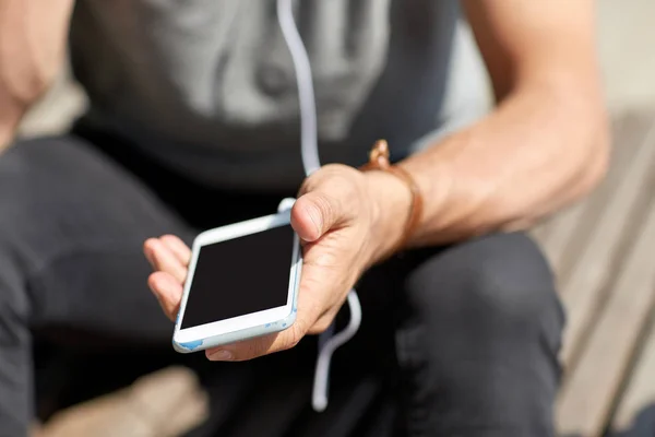 Närbild av man med smartphone och hörlurar tråd — Stockfoto