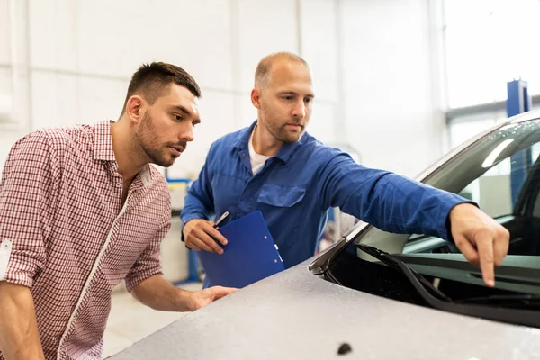 Auto mekaniker med Urklipp och man på bilverkstad — Stockfoto